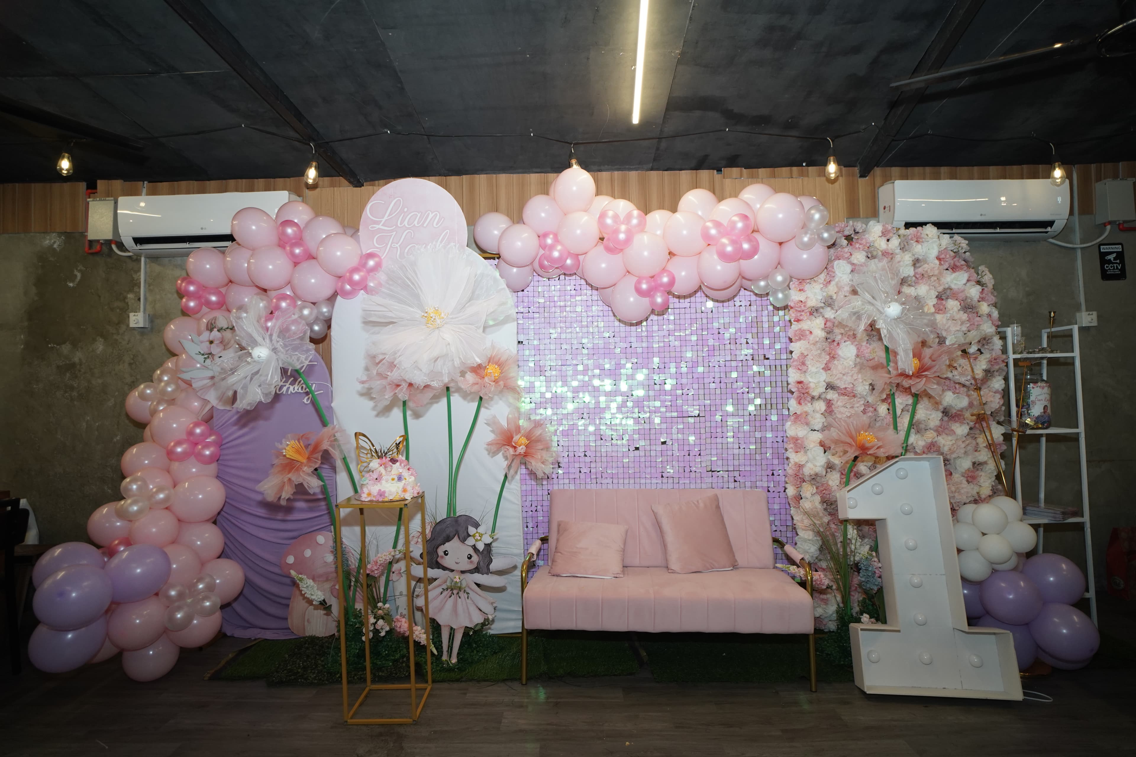 Lian Kayla fairy 1st birthday photo nook with pink sofa, giant flowers and fairy characters