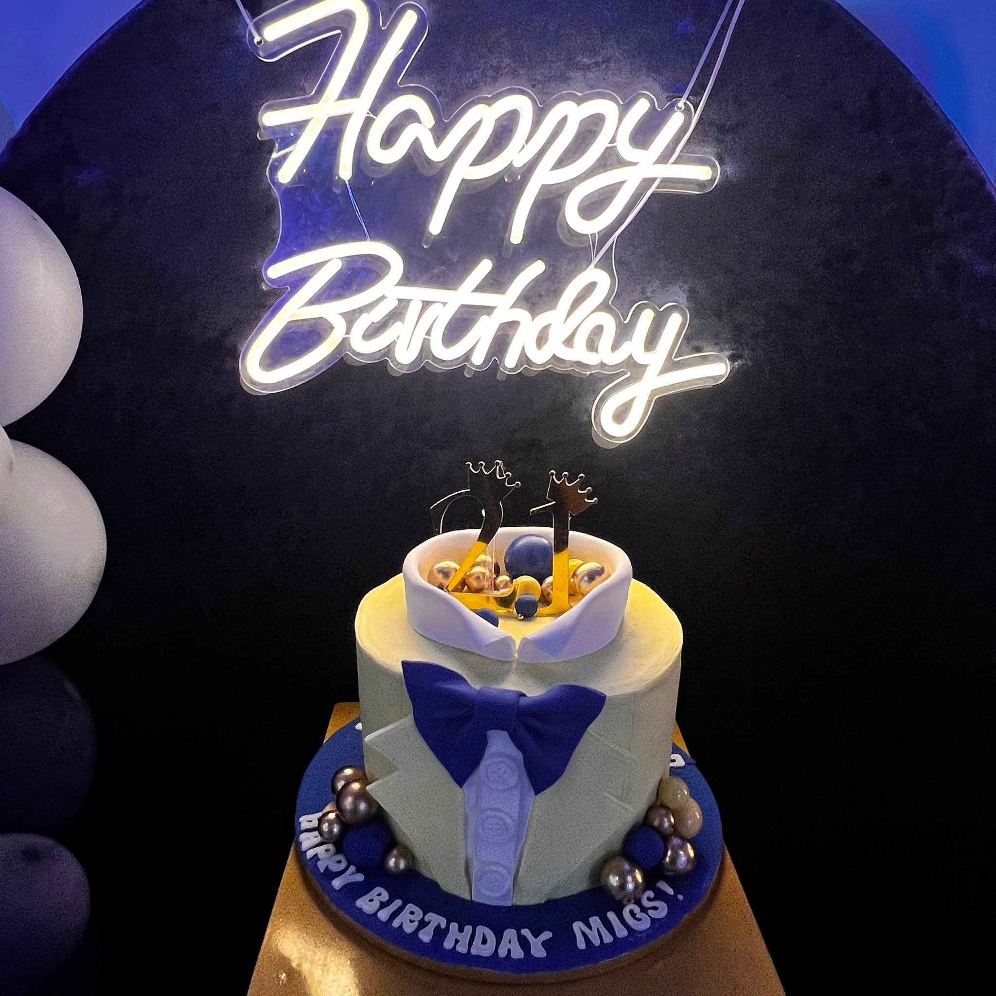 Elegant navy and gold birthday cake with Happy Birthday neon sign