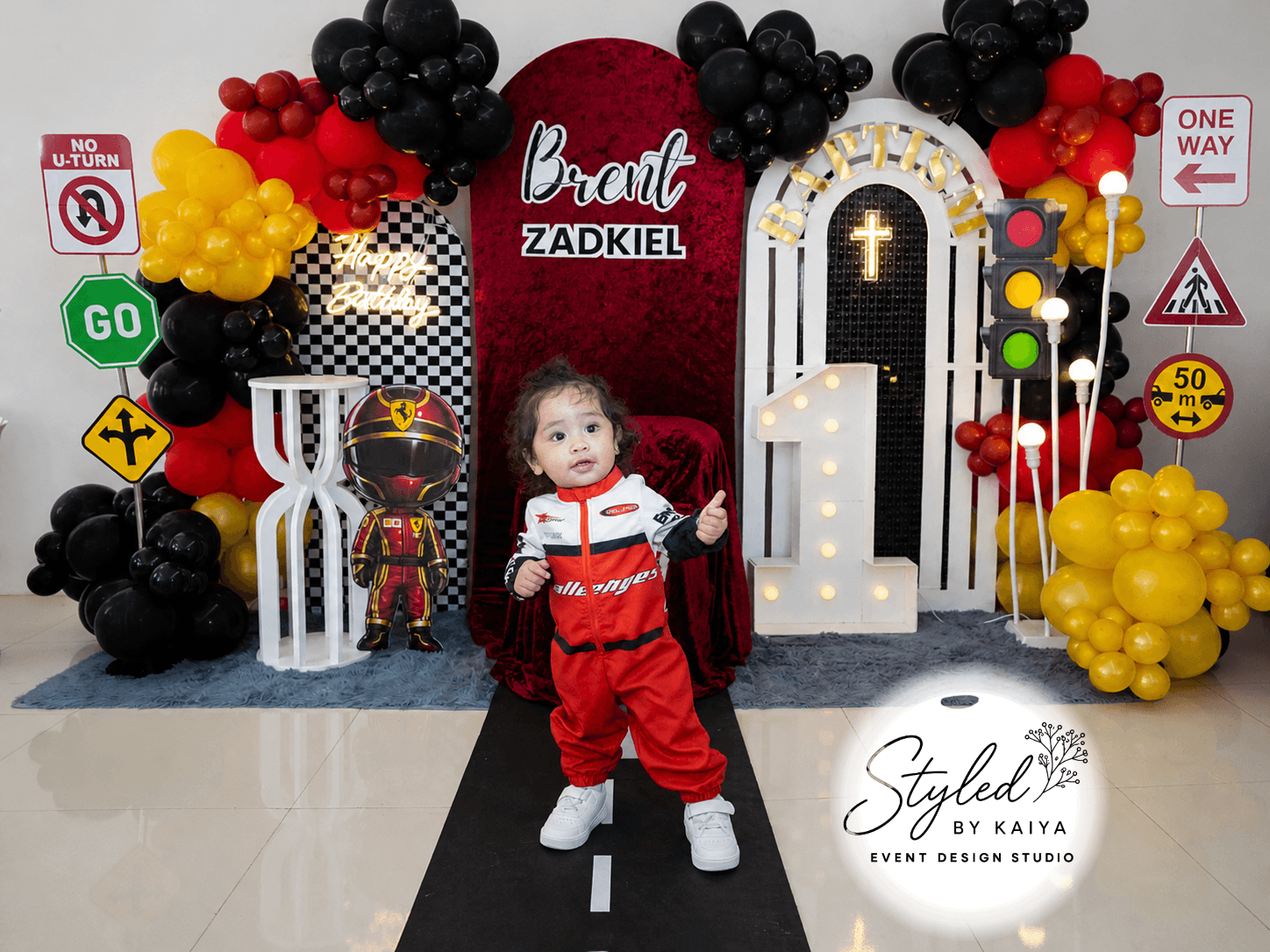 Brent Zadkiel in racing suit standing proudly at his baptism party backdrop