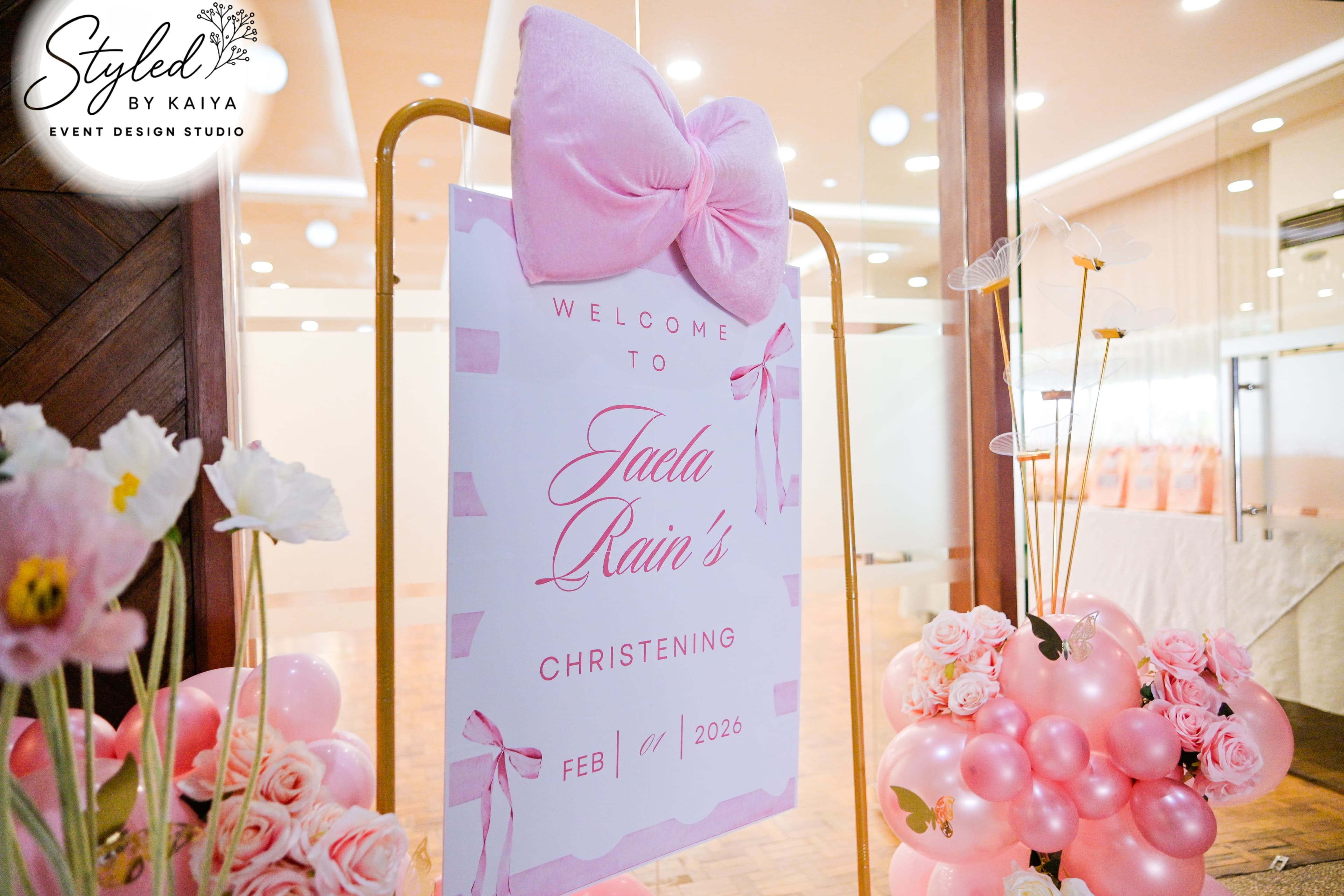 Welcome sign for Jaela Rain's christening with pink bow and flower accents