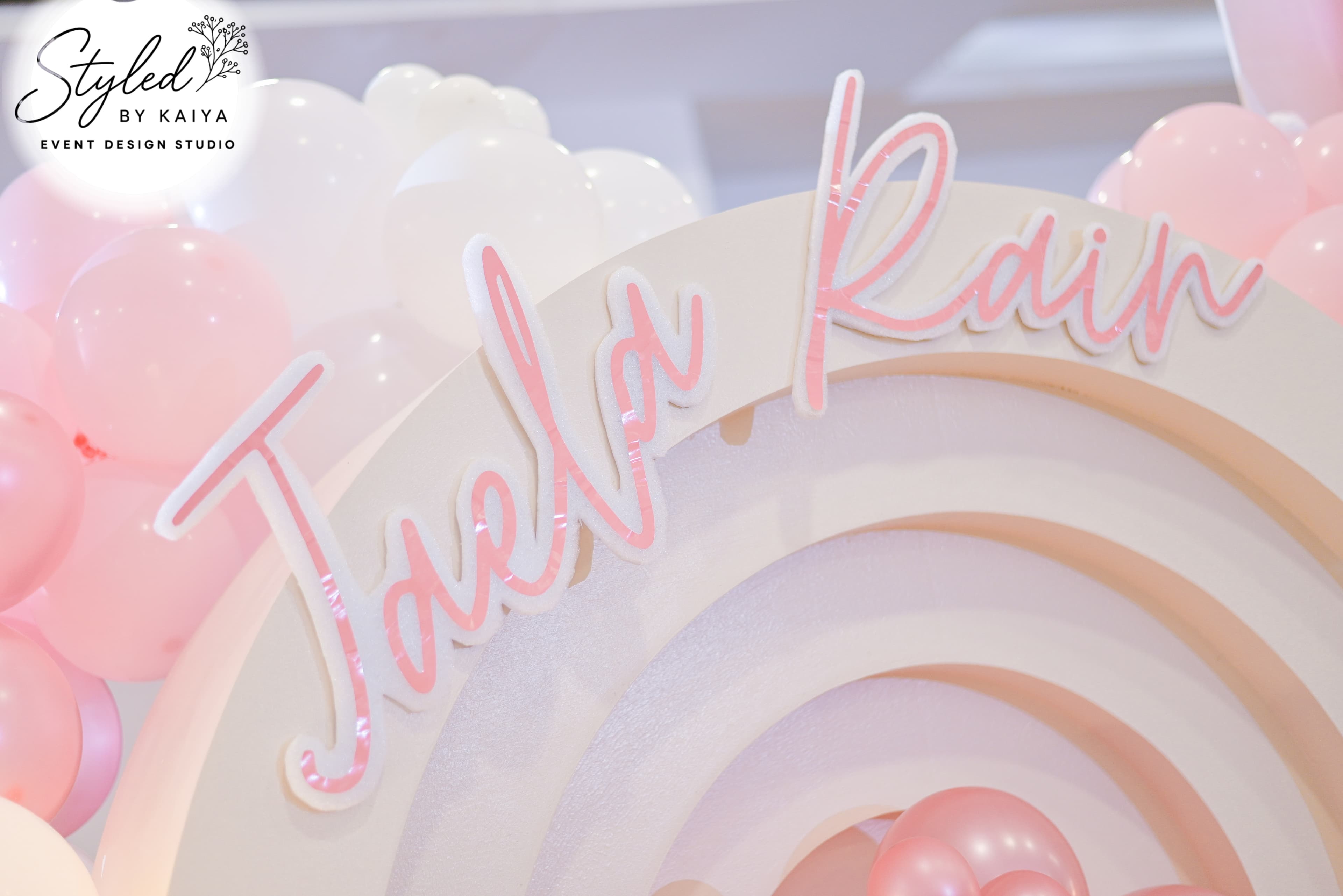 Jaela Rain name sign detail with soft pink balloons and cloud accents