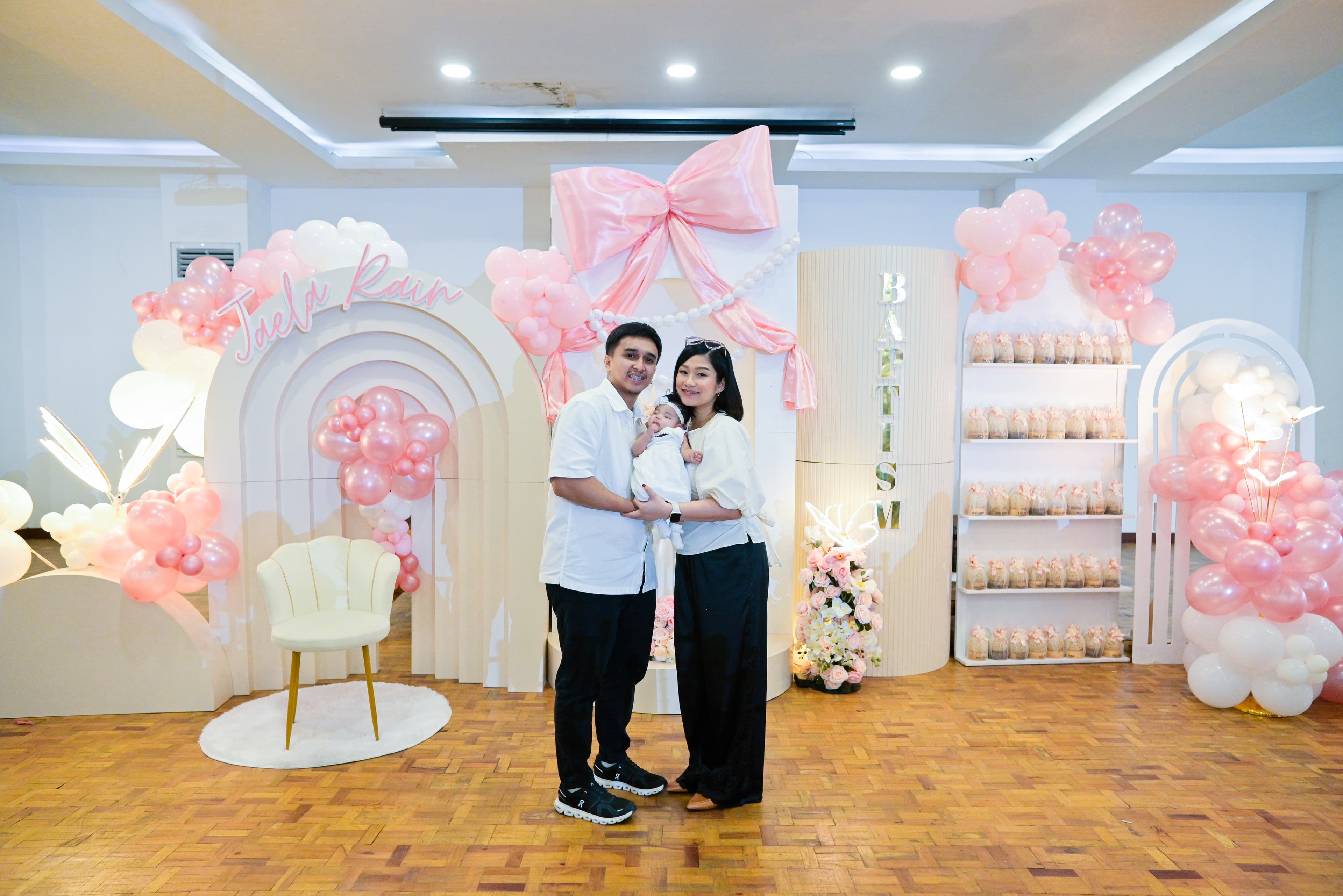 Parents with baby at Jaela Rain's pink and white christening backdrop