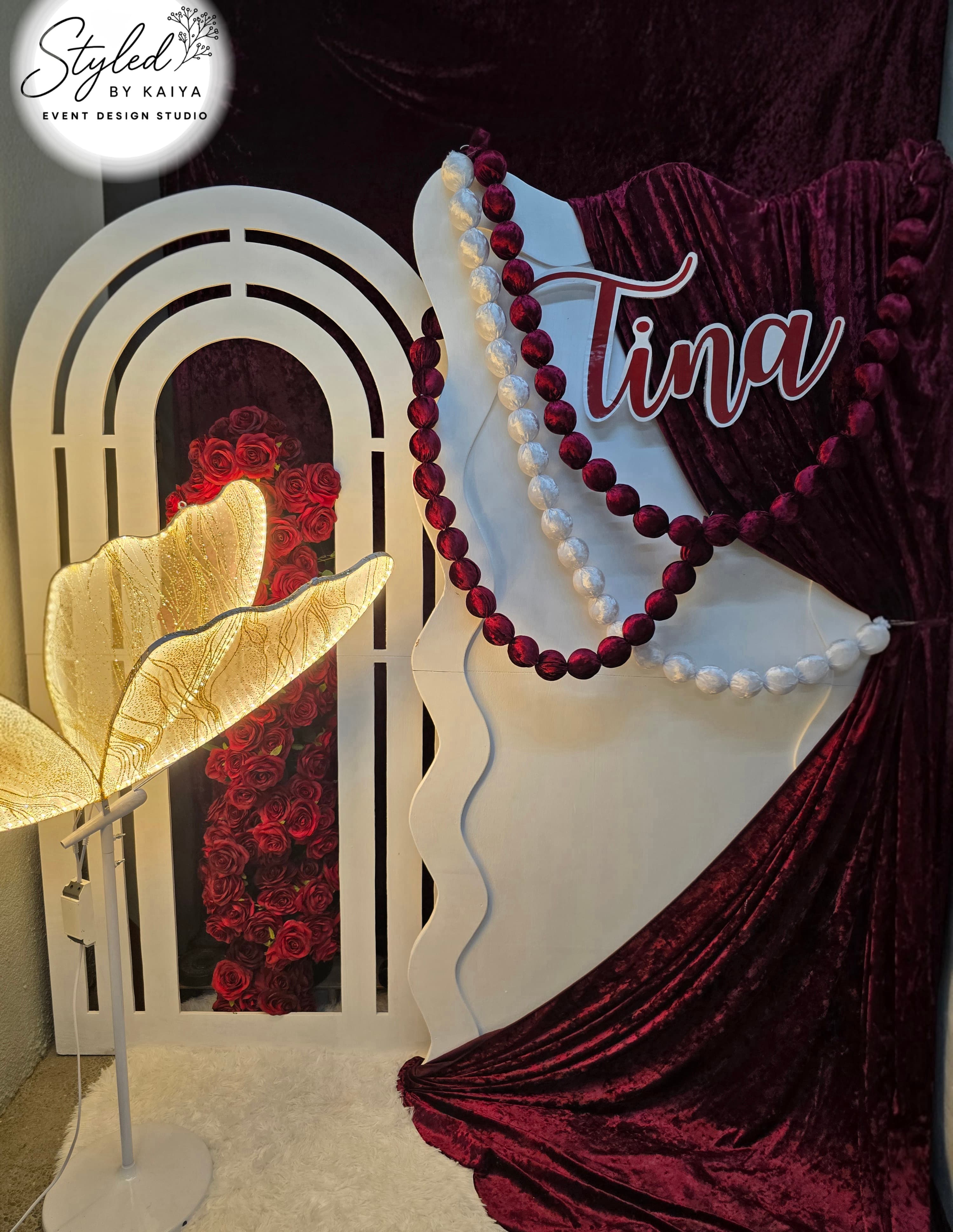 Tina's debut elegant burgundy arch with pearl garland and rose wall