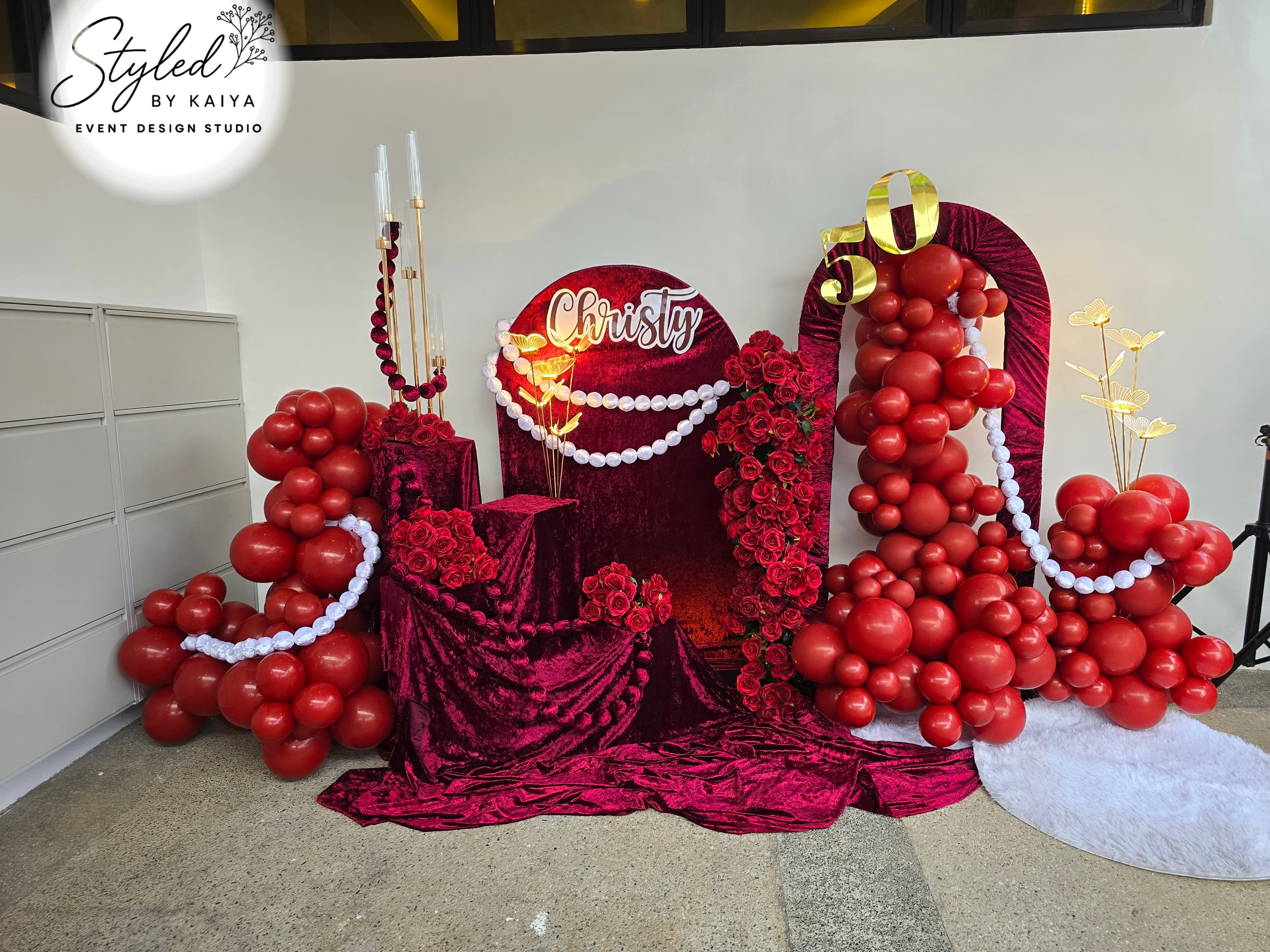 Christy's debut crimson velvet throne backdrop with red roses and gold chandelier
